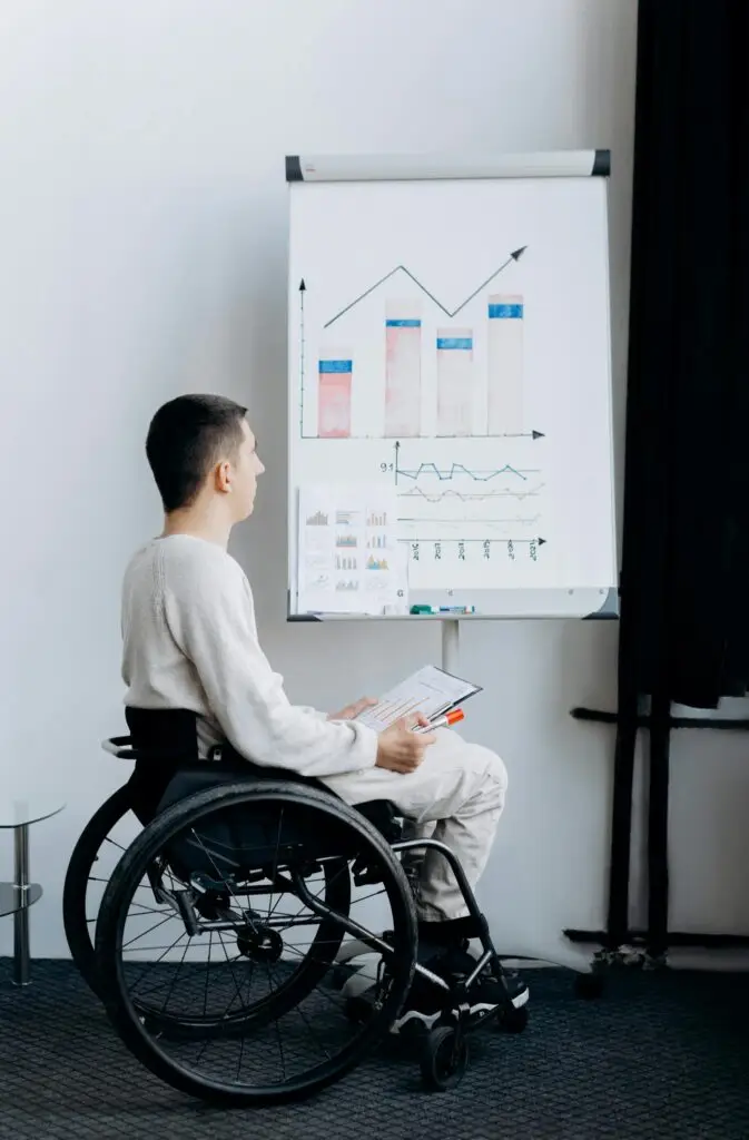 Man in wheelchair presenting data on a graph during a business meeting.